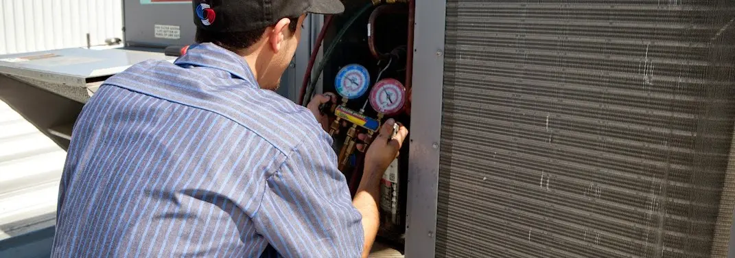 HVAC technician servicing a condenser unit in Romulus